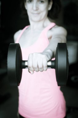 Spor salonunda 4 kilo ağırlıkla egzersiz yapan bir kız.