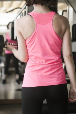 Spor salonunda 4 kilo ağırlıkla egzersiz yapan bir kız.