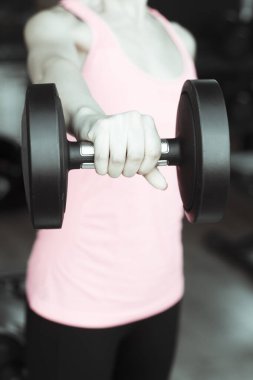 Spor salonunda 4 kilo ağırlıkla egzersiz yapan bir kız.