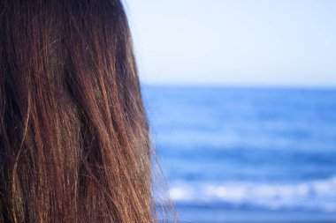 Sırtında kadın başıyla sahili görmek. Kahverengi saçlı