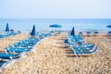 Gün batımında kumsalda şezlonglar. Kimse yok.