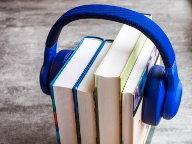 Concept of audiobook. Books on the table with headphones put on them clipart