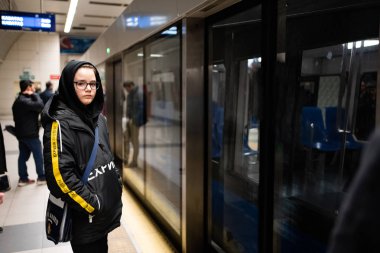 Teenager in glasses waiting for a subway train
