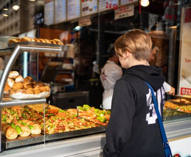 teenager stands at counter street food, rear view