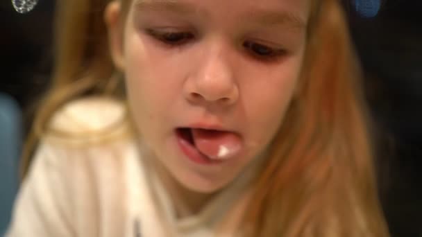Klein meisje blond met staarten eet een pannenkoek. Close-up. — Stockvideo
