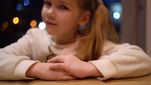 A menina loira sentada na mesa e acorda . — Vídeo de Stock