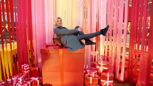 Blonde sits on a big box. Decoration for Valentine — Stockvideo