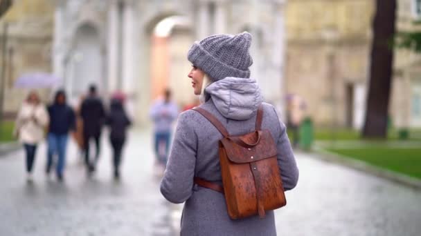 Chica de nuevo en abrigo y sombrero en la calle en la lluvia — Vídeos de Stock