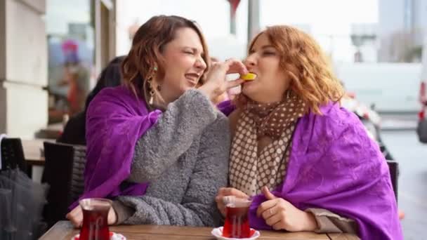 Two girlfriends sitting in a cafe and eat a lemon. — Stock videók