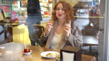 Kafedeki kızıl kız tatlı yiyor.