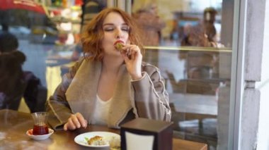 Kafedeki kızıl kız tatlı yiyor.