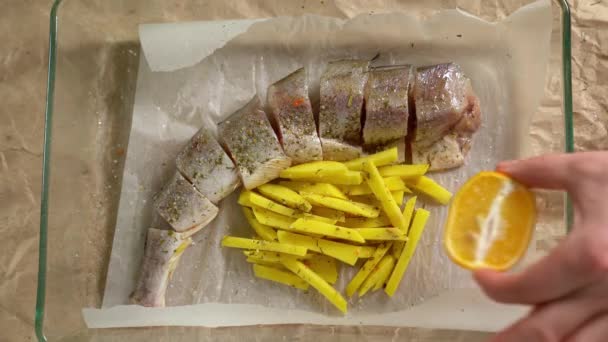 Cooking. Fish and potatoes on pan, put lemon — ストック動画