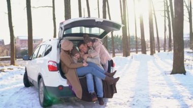 Family with daughters sitting in the trunk of car