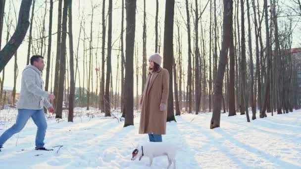 Parents hugging in woods and daughter throws snow — Stockvideo