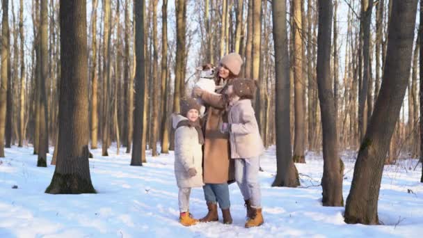 Mother with two daughters and dog in snowy forest — 图库视频影像