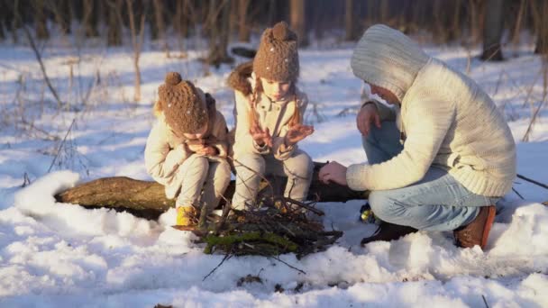 Pai, filhas sentadas fogueira na floresta de inverno — Vídeo de Stock