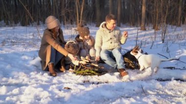 Family roast on the campfire weenies in the winter