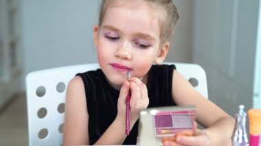 Little girl doing the makeup yourself at home. Beauty blogger. Lipstick.