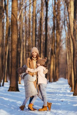 Mother and daughters hugging in winter snow forest