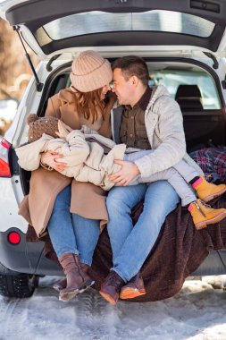 parents with their daughter in the trunk of a car