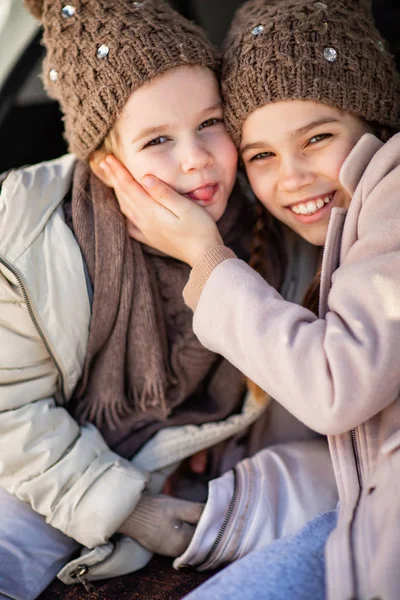 Two sisters sitting in the trunk of a car and hug — Stockfoto
