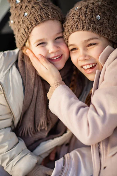 Two sisters sitting in the trunk of a car and hug — Stockfoto