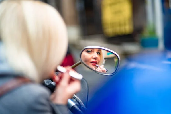 Rubia pintalabios mirando en el espejo en una moto — Foto de Stock