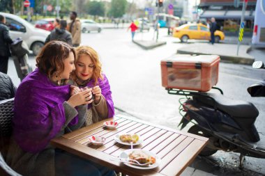 Bir kafede oturup çay içen iki kız arkadaş.