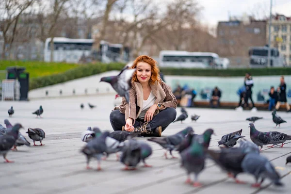 Дівчина сидить на площі і навколо голубів — стокове фото