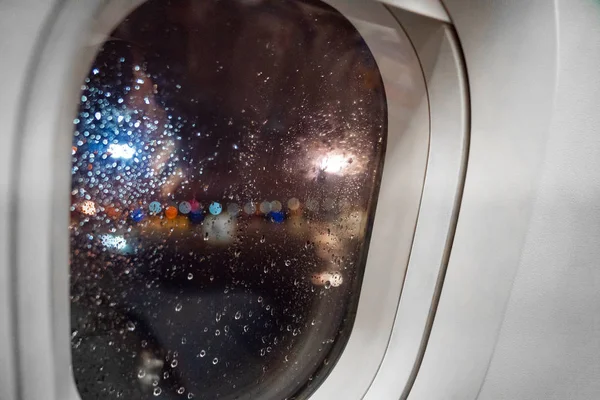 Colored drops on window at night on plane window — Stock Photo, Image