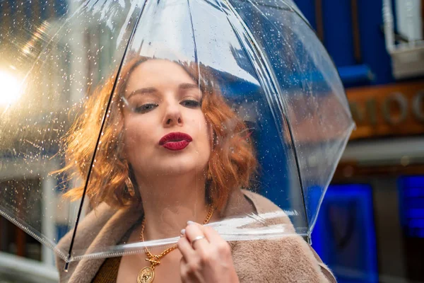 red-haired girl brown clothes under umbrella kiss