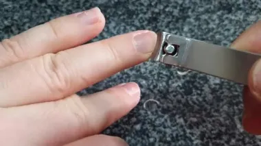 cutting nails on a man's hand with nail tongs