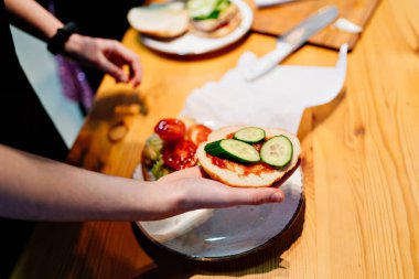 Hamburger pişir. Ketçaplı ekmek ve salatalık eli.