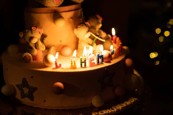 Bolo de aniversário com urso e velas no escuro — Fotografia de Stock