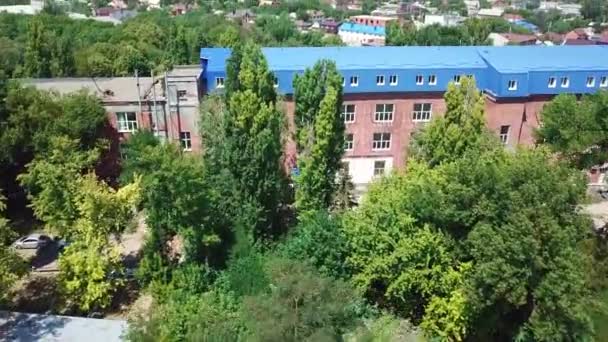 Flying over house with blue roof and green trees — 图库视频影像