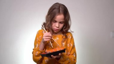 Teen girl learns how to hold chopsticks for sushi