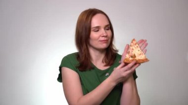 A woman takes slice of pizza and smells delicious