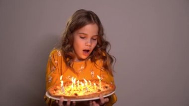 blonde girl blows out candles on birthday pizza