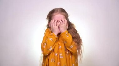 Frightened, little girl is afraid and hides face