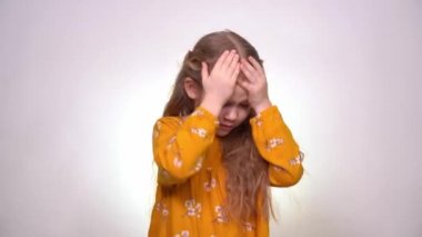 Headache little girl with blond hair, yellow dress