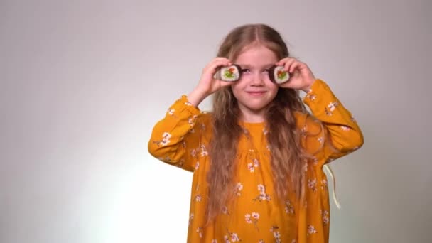 Little girl holding rolls as points and laughs. — Stok video
