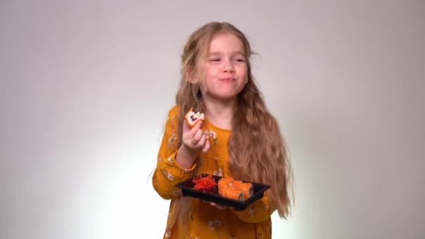 Маленькая девочка кусает вкусные роллы и держит в руках . — стоковое видео