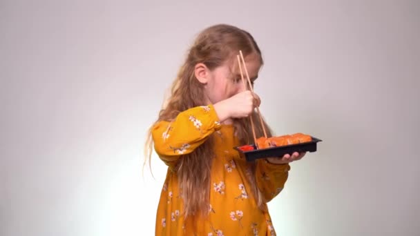 Little girl tries to take the roll with chopsticks — Wideo stockowe