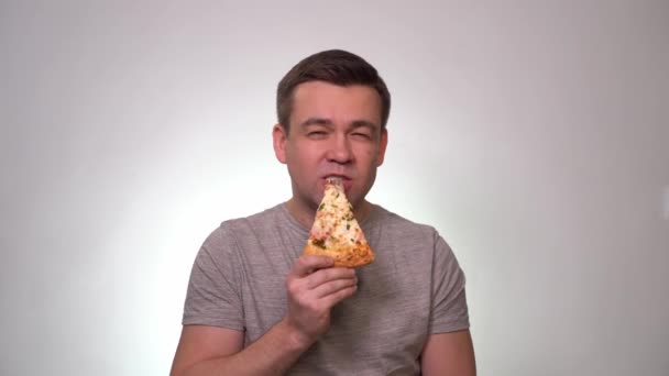 Man bites and eats a slice of pizza. Delicious. — ストック動画