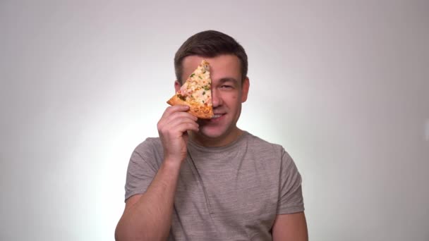 Man holding piece of pizza in front of their face — ストック動画