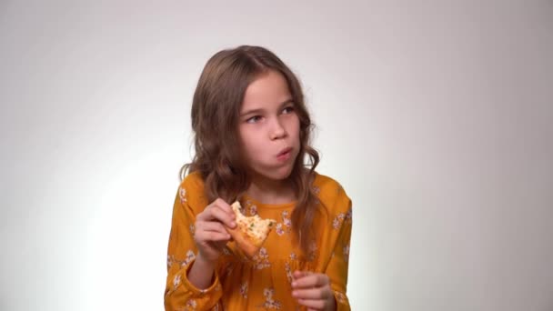 Teen girl eating pizza, laughing, white background — Stockvideo