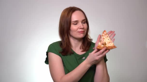 Una mujer toma rebanada de pizza y huele delicioso — Vídeos de Stock