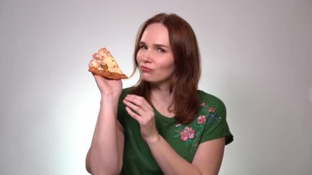 Una mujer de cabello castaño sosteniendo un pedazo de pizza, se ríe — Vídeo de stock
