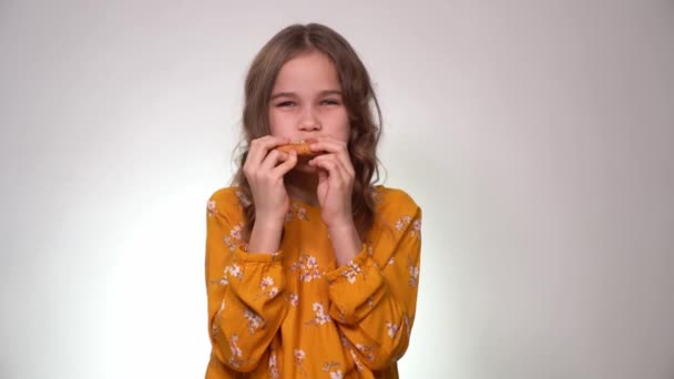 Девочка-подросток смеется, ест пиццу на белом фоне — стоковое видео
