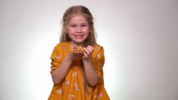 Little girl blonde laughs and bites pizza — ストック動画